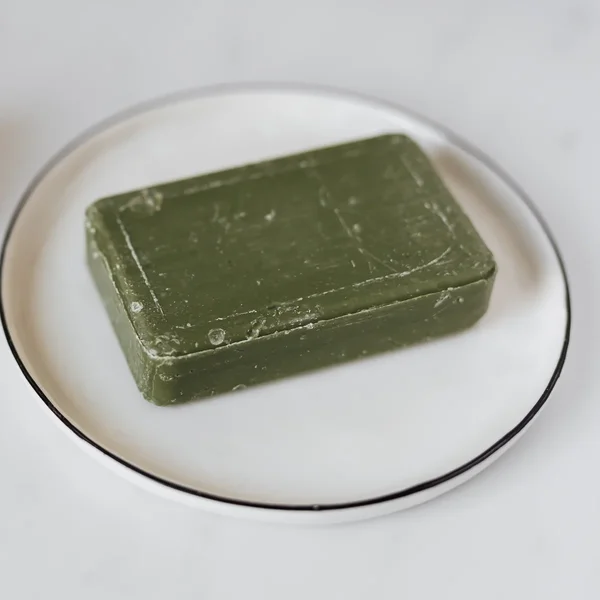 Pain de savon vert olive sur une assiette blanche