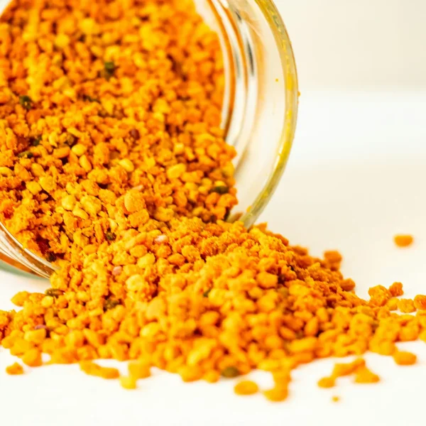 Pelotes de pollen jaune orangé qui se déversent d’un bocal en verre